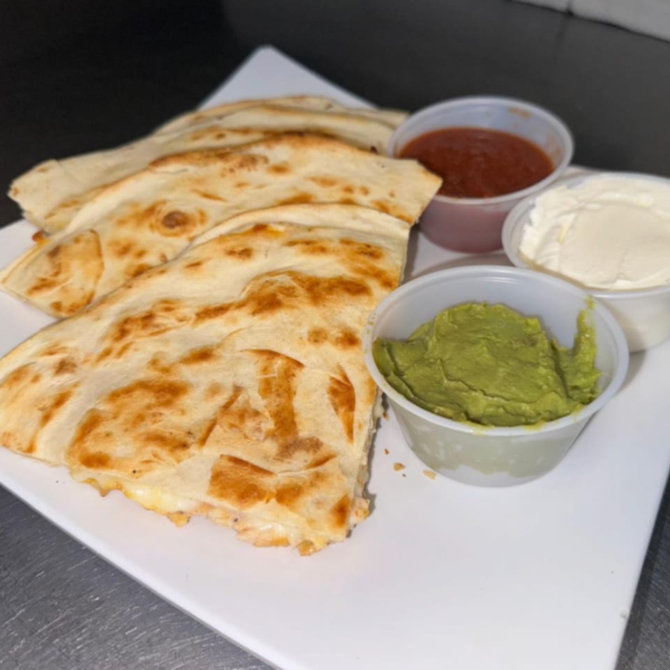 Golden-brown quesadillas with guacamole, salsa, and sour cream on a white plate.