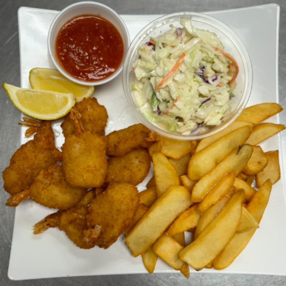 Fried shrimp, steak fries, coleslaw, cocktail sauce, and lemon wedges on a white plate.